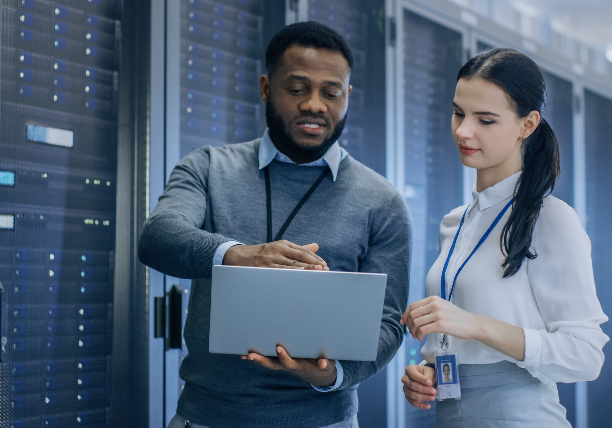 Black IT Technician with a Laptop Computer Gives a Tour to a You IT recruitment
