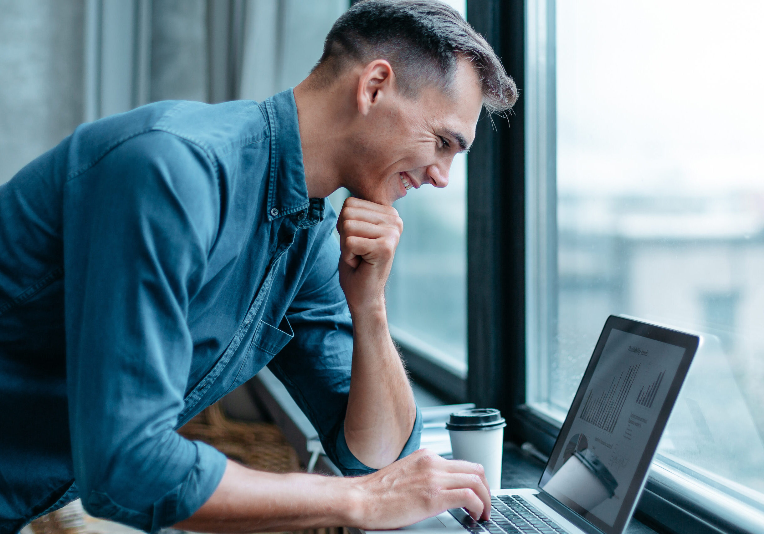 man with a laptop standing near the window . people and technology .