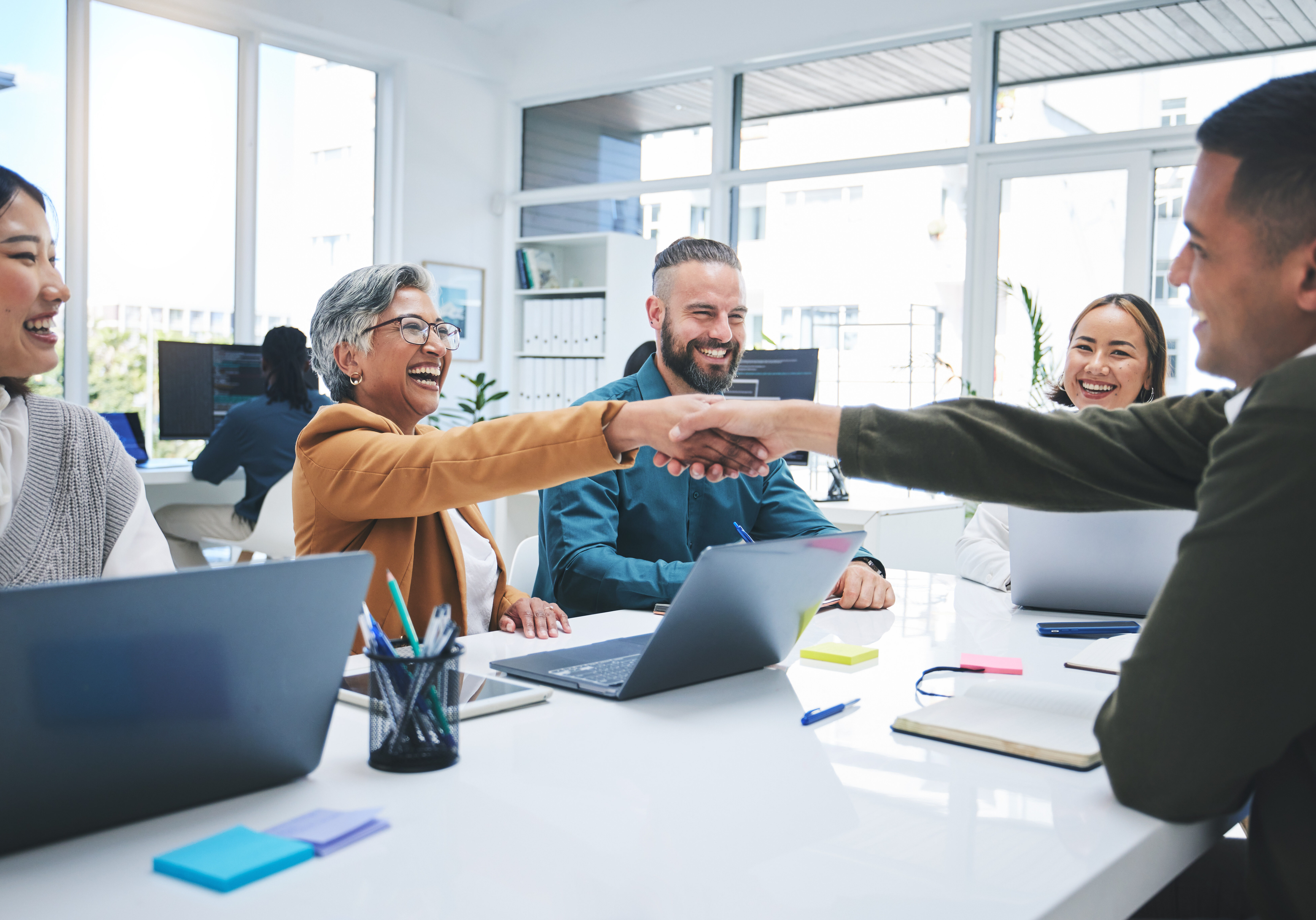 Creative people, handshake and meeting in hiring, partnership or deal agreement together at the office. Group of employees shaking hands in recruiting, company growth or startup at the workplace.